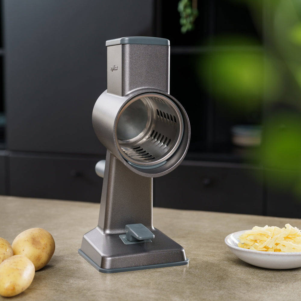The Zyliss Gourmet Drum Grater Set features a gray base, two interchangeable stainless steel drums, and comes in a branded cylindrical box—an essential tool for any kitchen. 