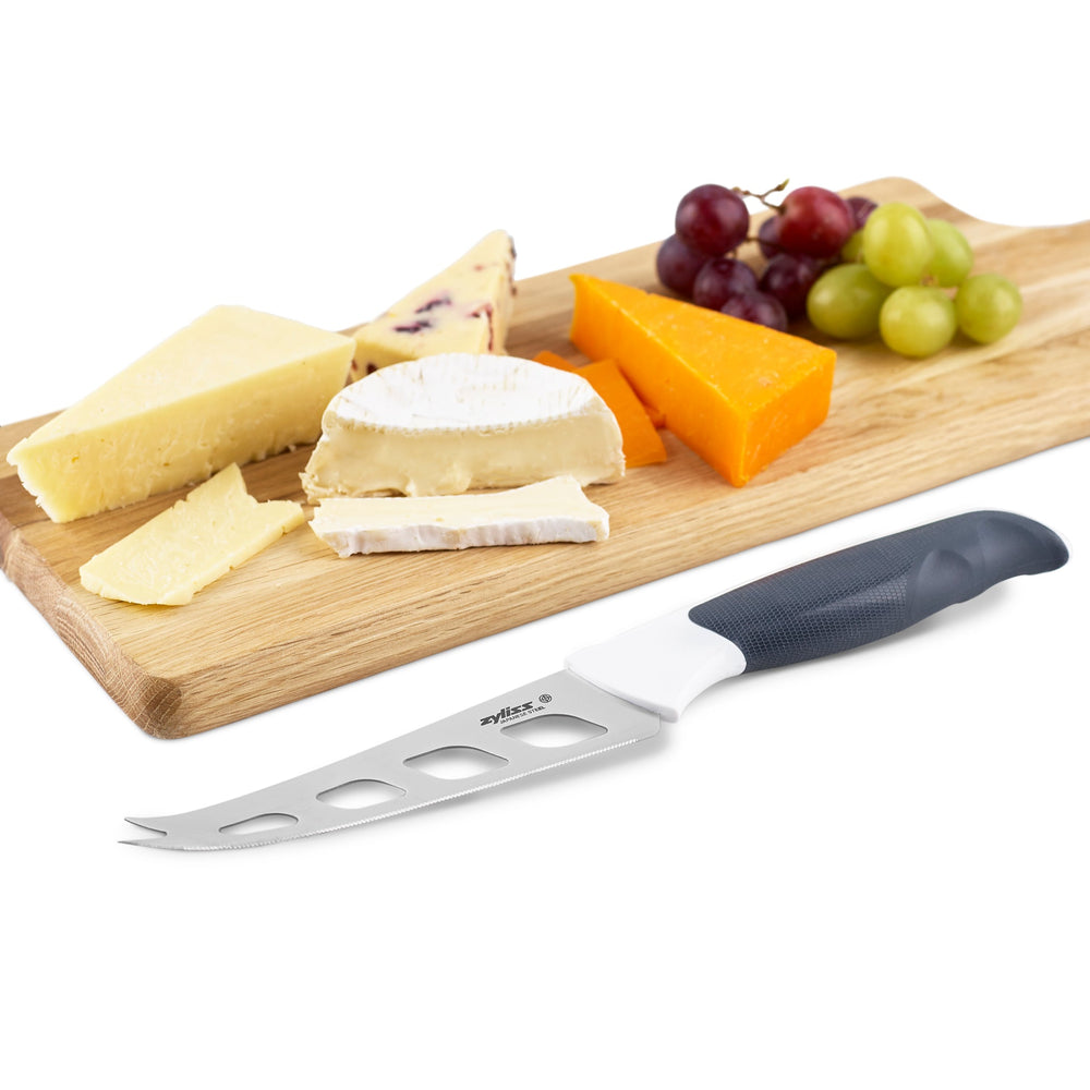 The Zyliss Comfort Cheese Knife 12cm / 4¾, with an ergonomic handle, partially serrated blade with large cut-out holes, and matching black blade cover, is placed beside it on a plain light background. 
