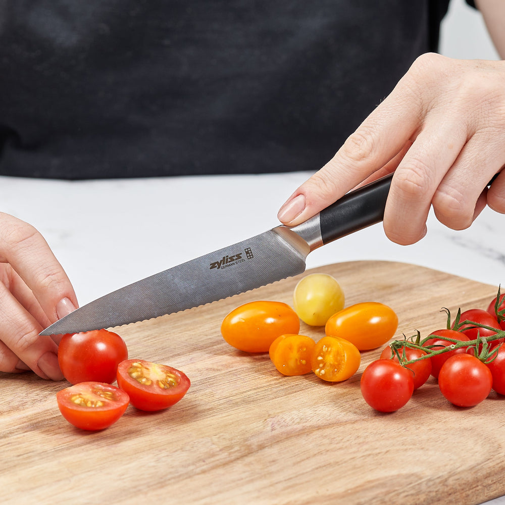 The Zyliss Comfort Pro Serrated Paring Knife 11cm, featuring a German stainless steel blade and ergonomic black handle, is displayed vertically against a plain light background. 