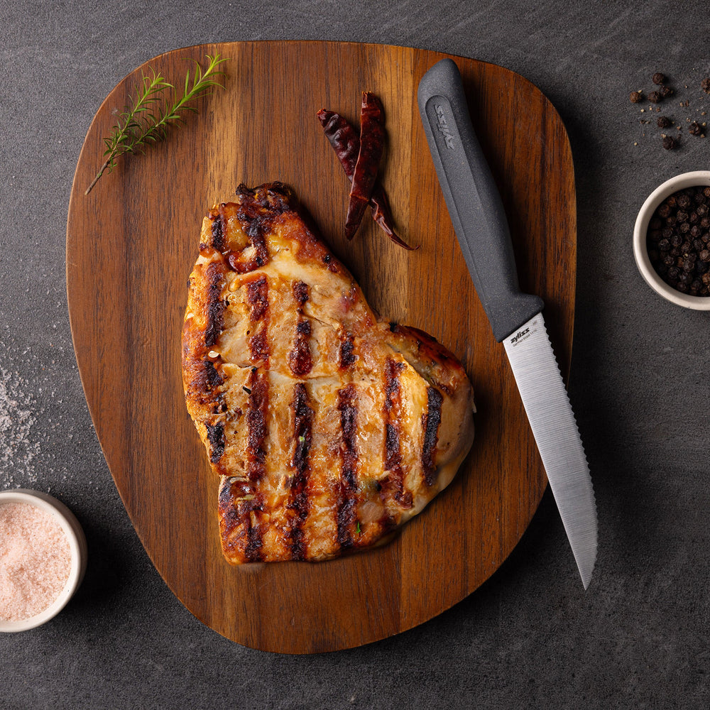 The Zyliss Steak Knife Serrated 11cm / 4½ features a silver blade and an ergonomic dark gray plastic handle, displayed against a plain light background. 