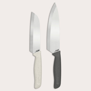 The Zyliss Classic 2 Piece Chef & Santoku Knife Set features two kitchen knives with shiny stainless steel blades—one with a sleek white handle and the other with a black handle. Both the chef knife and santoku blade stand upright against a plain, light background.