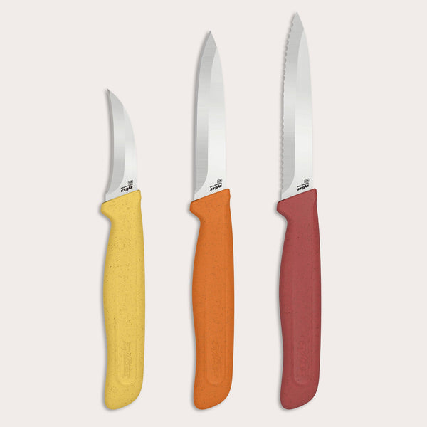 Three knives from the Zyliss Classic 3 Piece Peeling & Paring Knife Set displayed upright against a light background, each with a stainless steel blade and a speckled handle in yellow, orange, or red; the rightmost knife has a serrated blade.